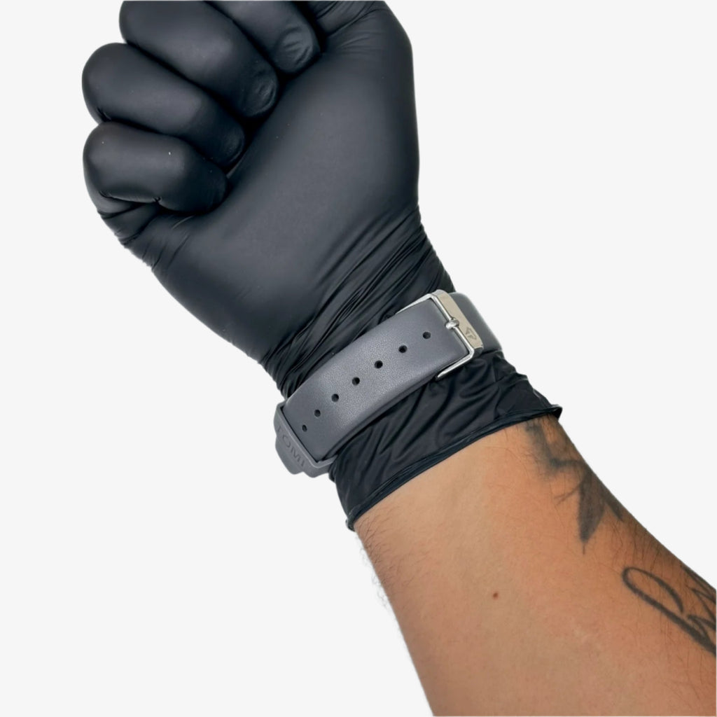 Black glove on a wrist with a gray belt against a gray background