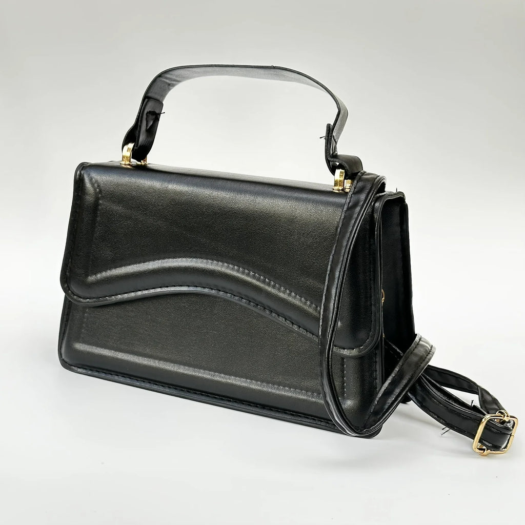 Black handbag with gold accents on a light gray background