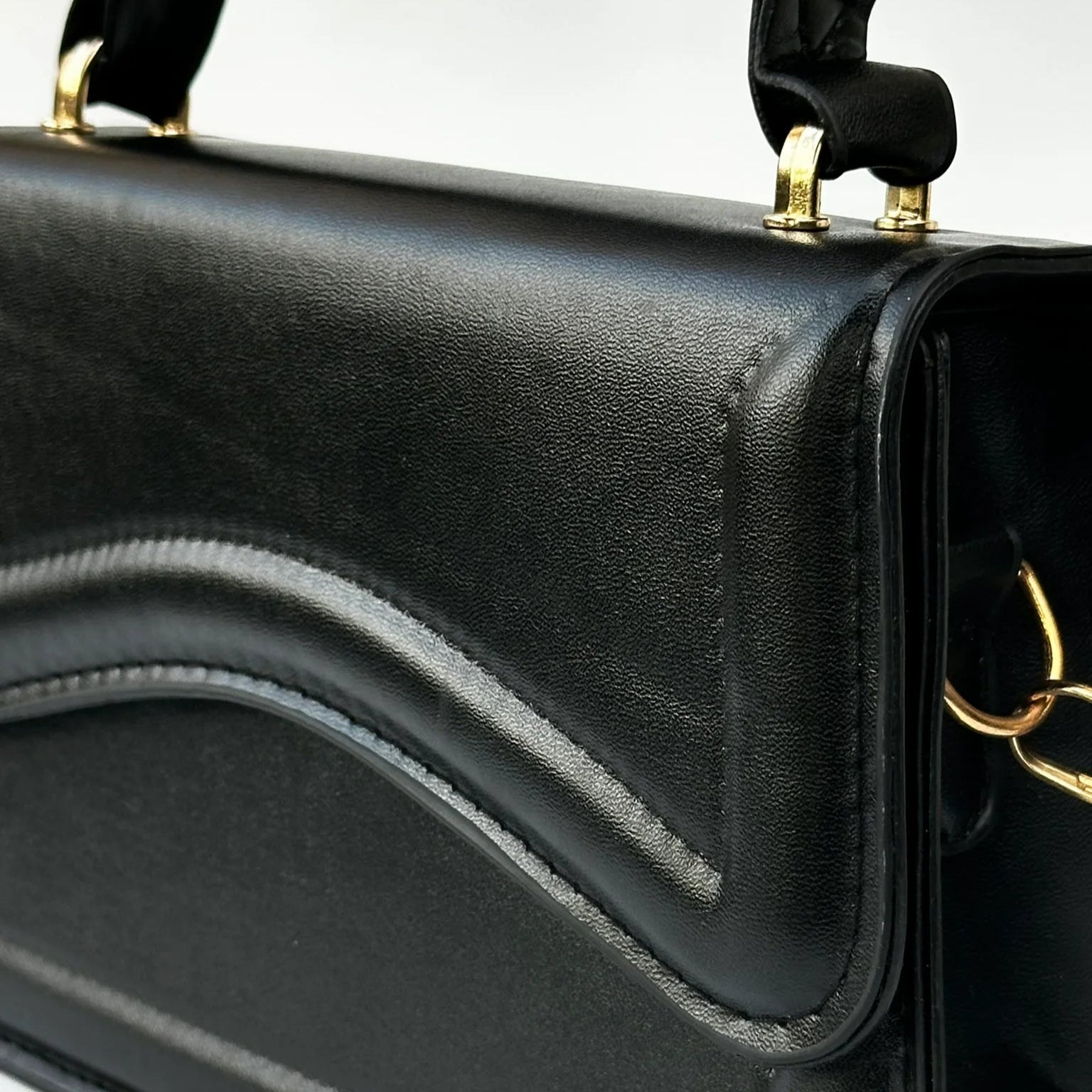 Black handbag with gold accents on a white background