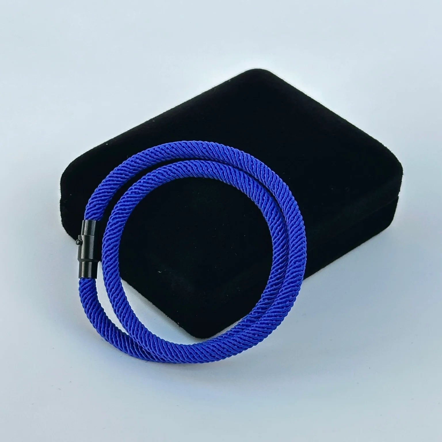 Blue braided cable on a black rectangular block against a white background