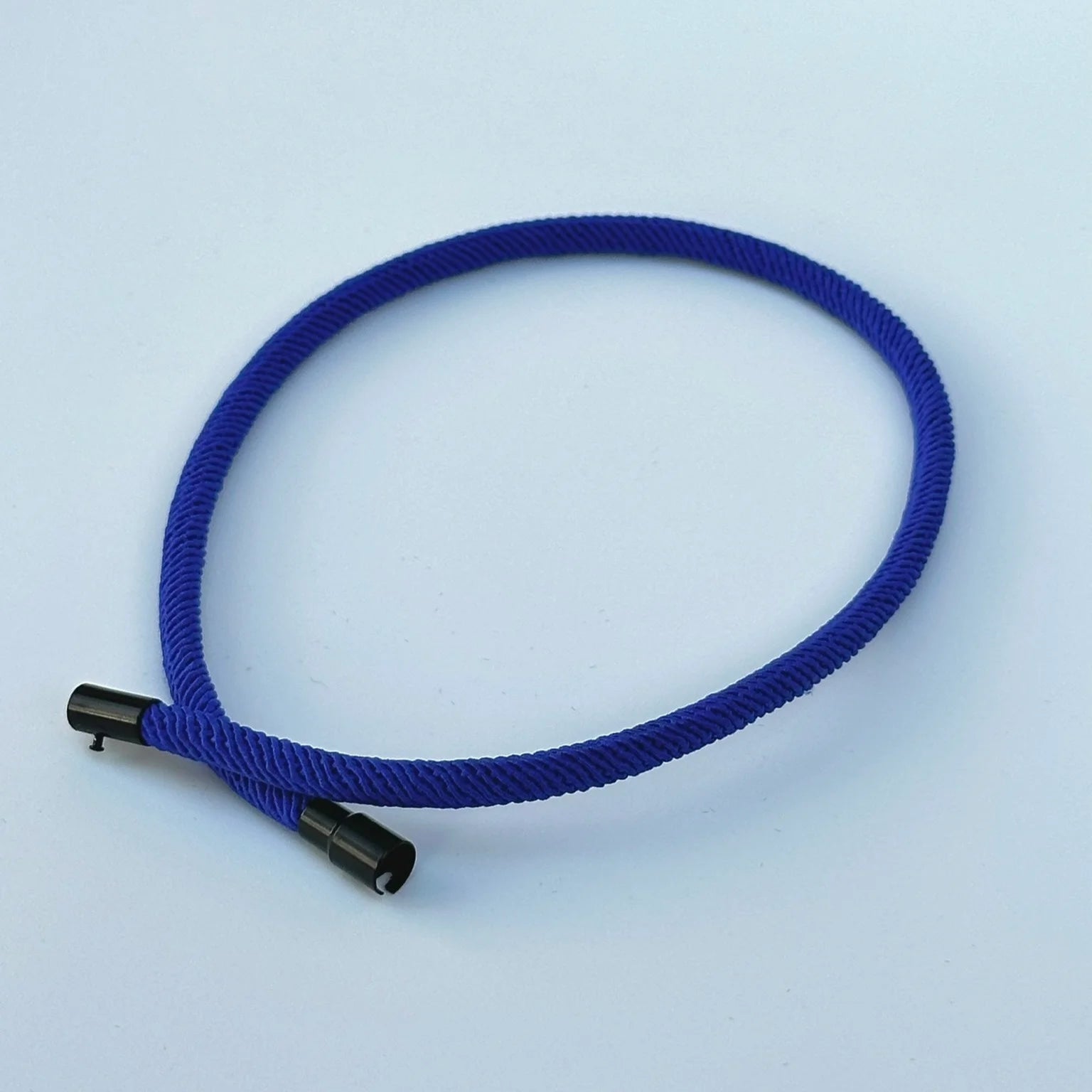Blue hair tie with black ends on a light blue background