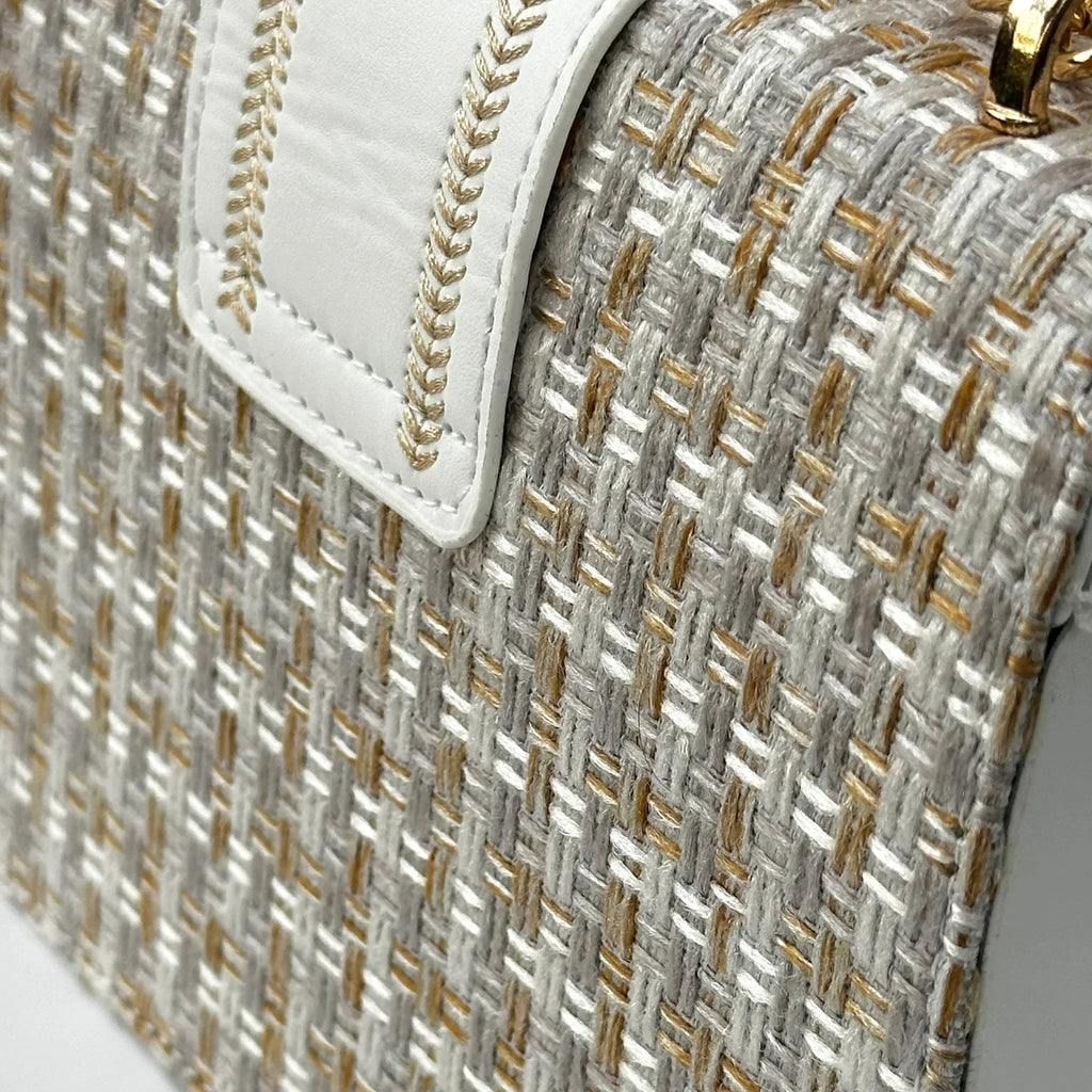 Close-up of a textured handbag with gold and silver pattern on a light gray background