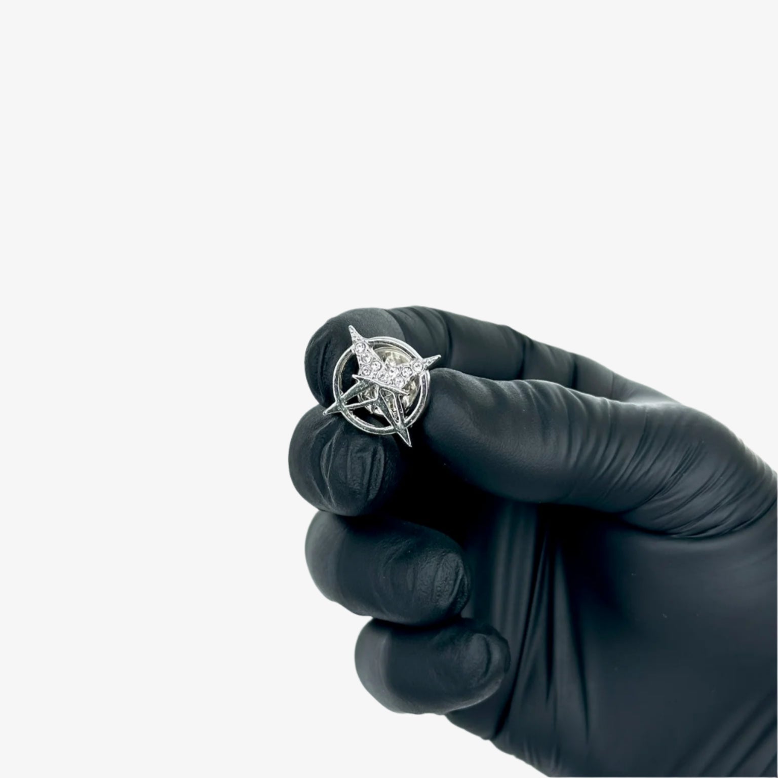 Diamond ring held by a gloved hand against a light gray background