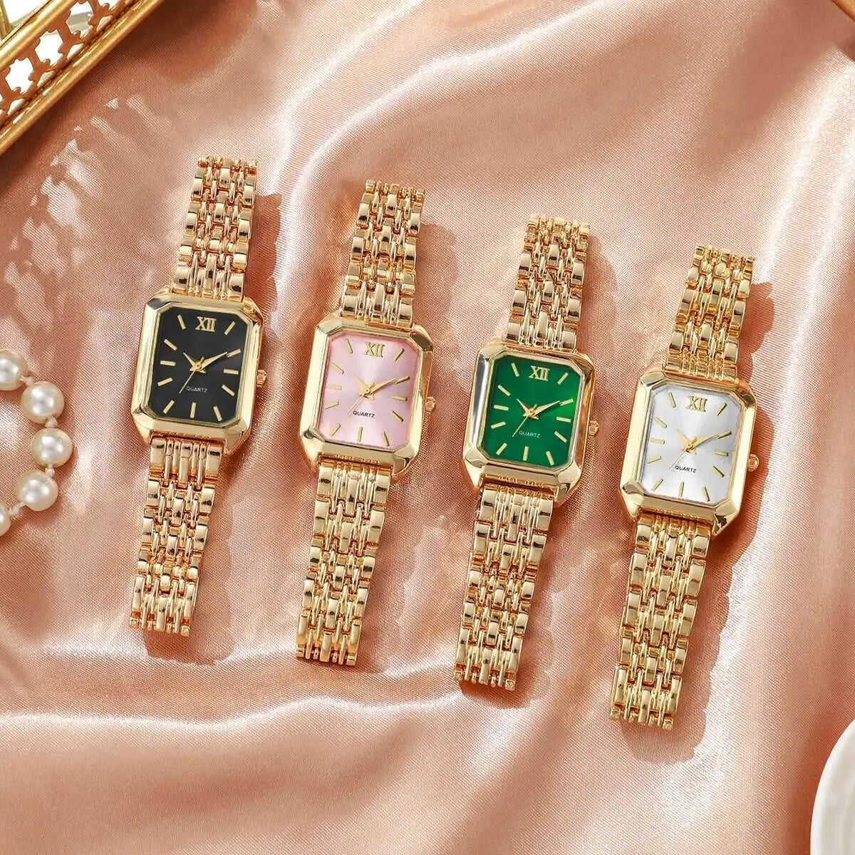 Four gold wristwatches with different colored faces on a pink fabric background