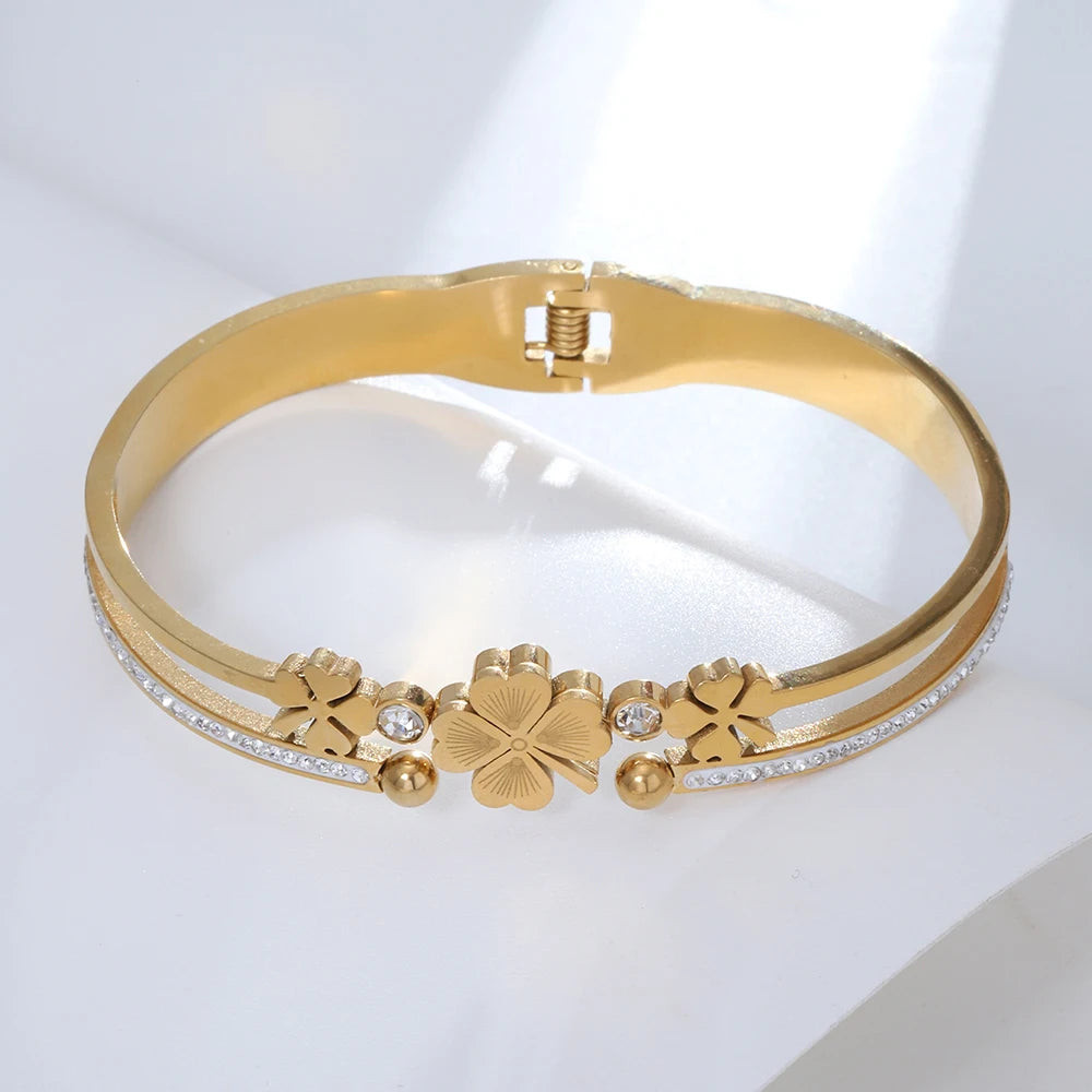 Gold bracelet with floral designs and clear stones on a white background