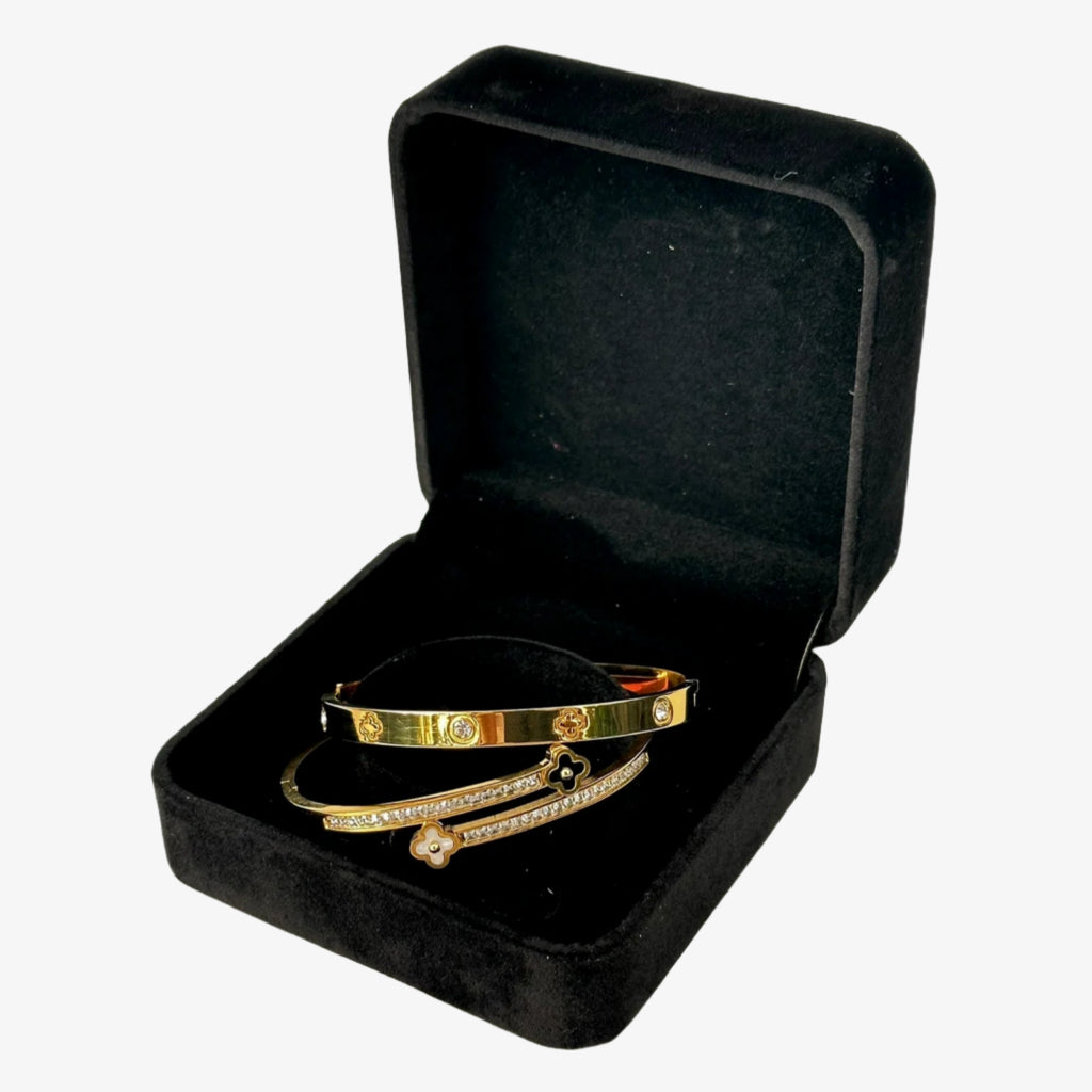 Gold bracelets in a black jewelry box on a white background