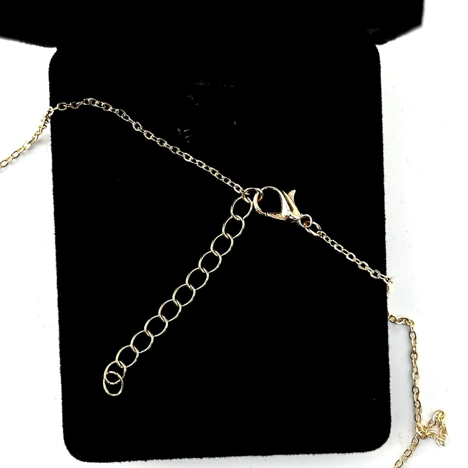 Gold chain necklace on a black display card with a white background