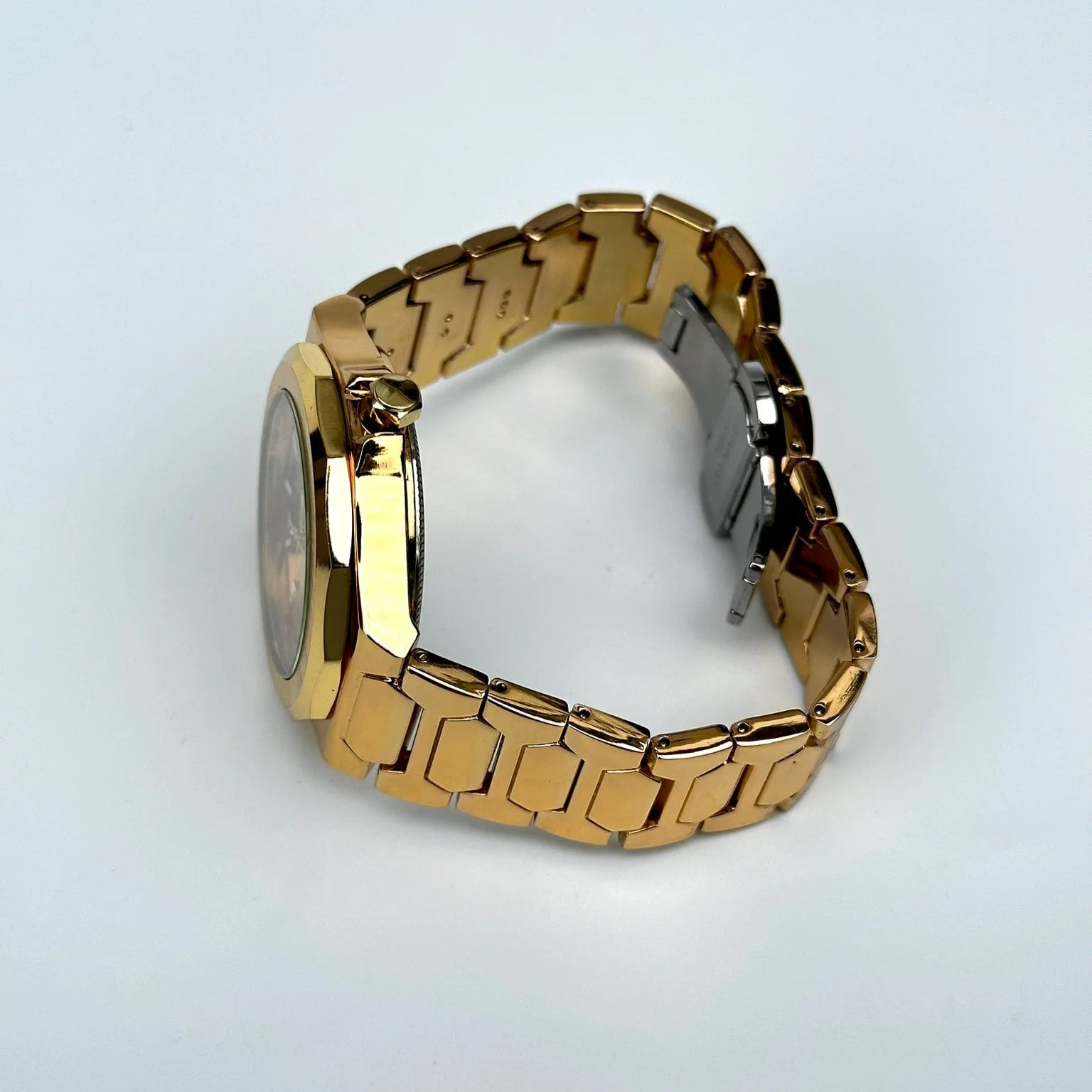 Gold metal watch on a light gray background