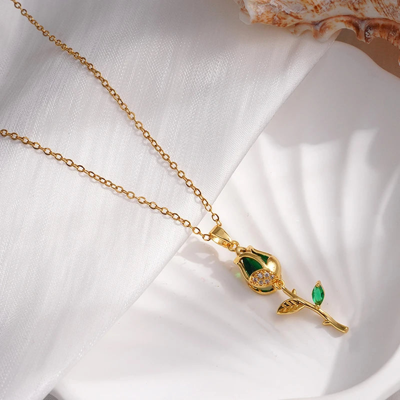 Gold necklace with a green gemstone pendant on a white fabric background