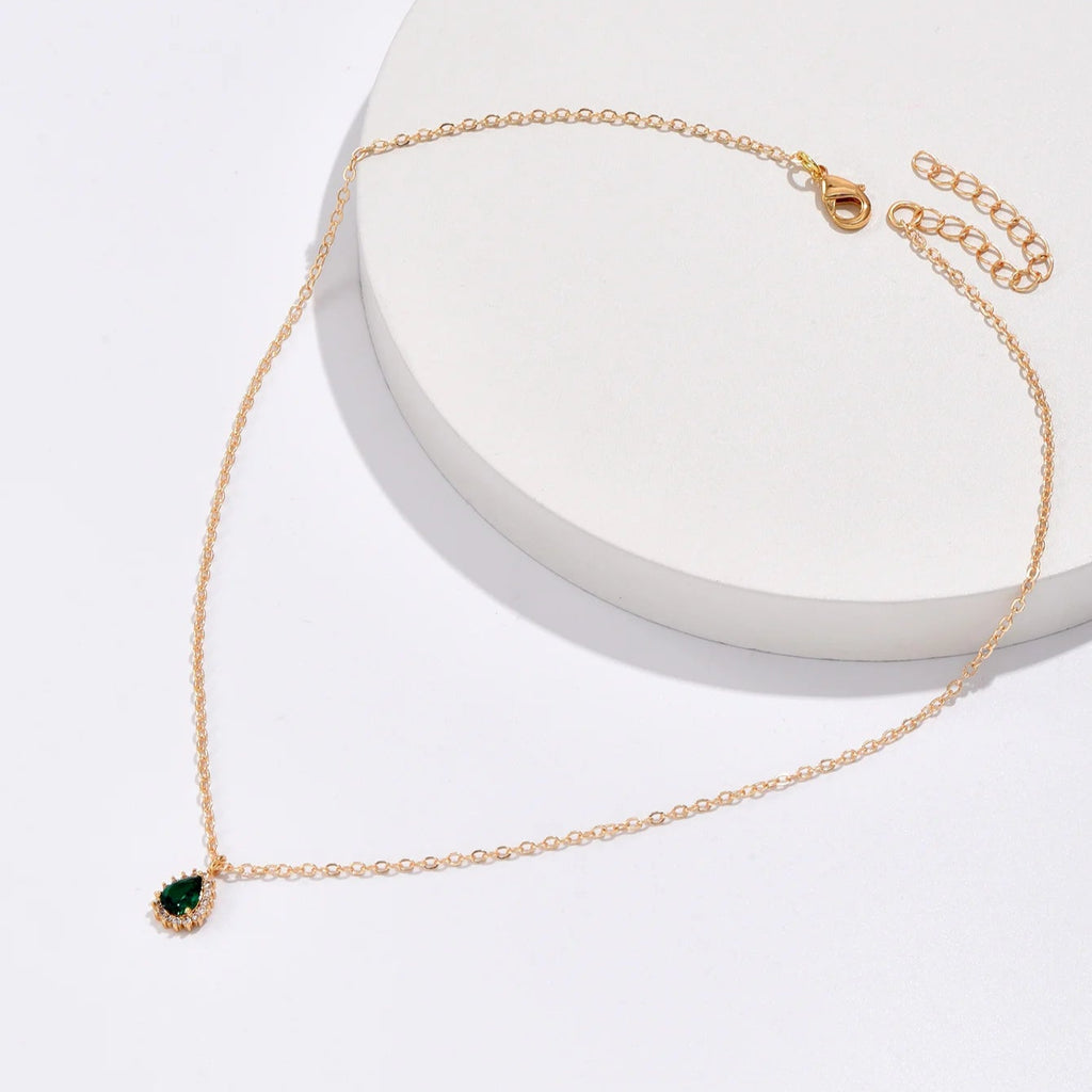 Gold necklace with a green pendant on a white background
