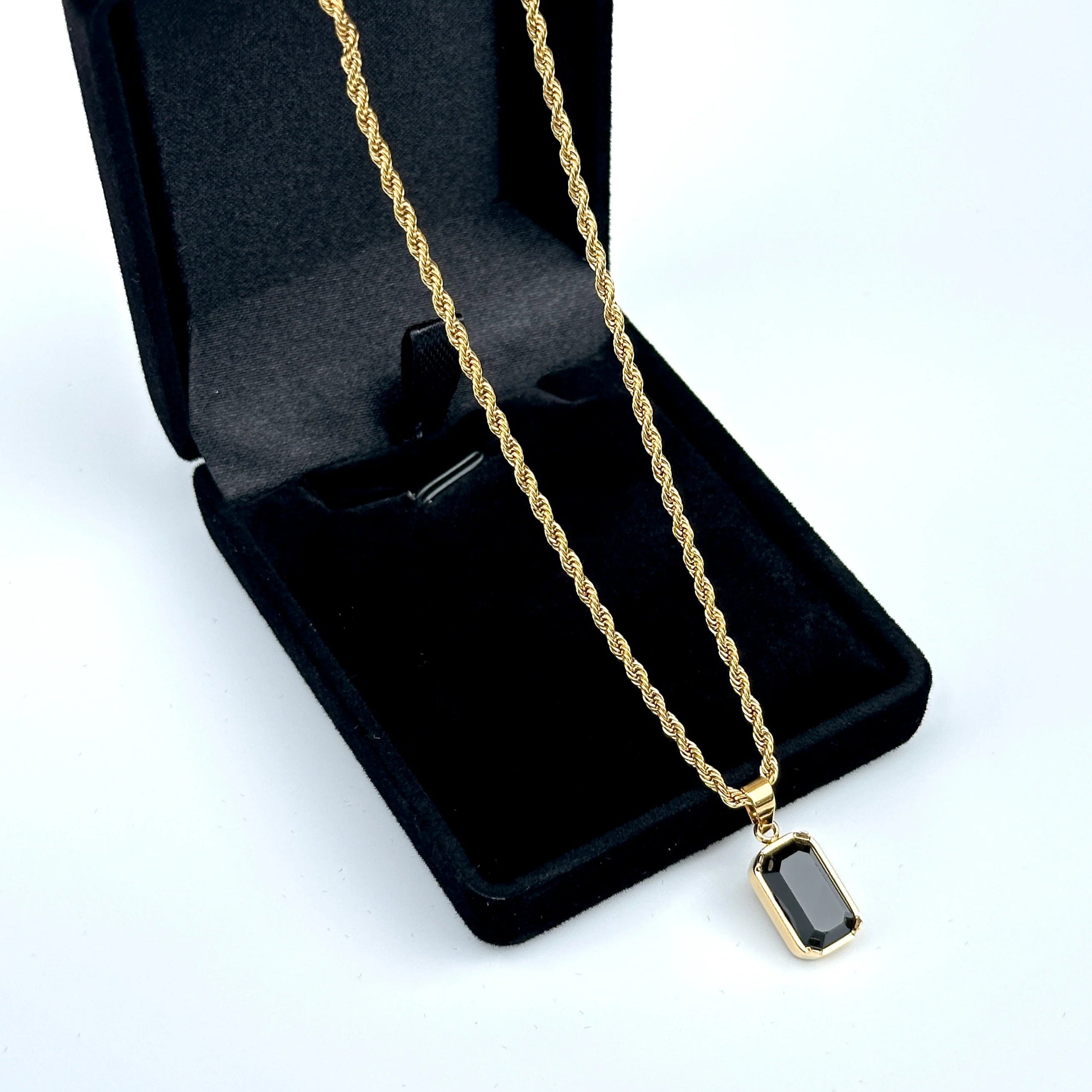 Gold necklace with a pendant in an open black jewelry box on a white background