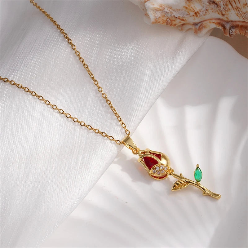 Gold necklace with a red and green gemstone pendant on a white fabric background