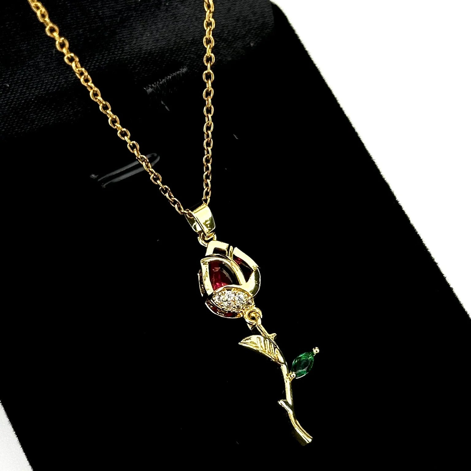 Gold necklace with a rose pendant on a black background