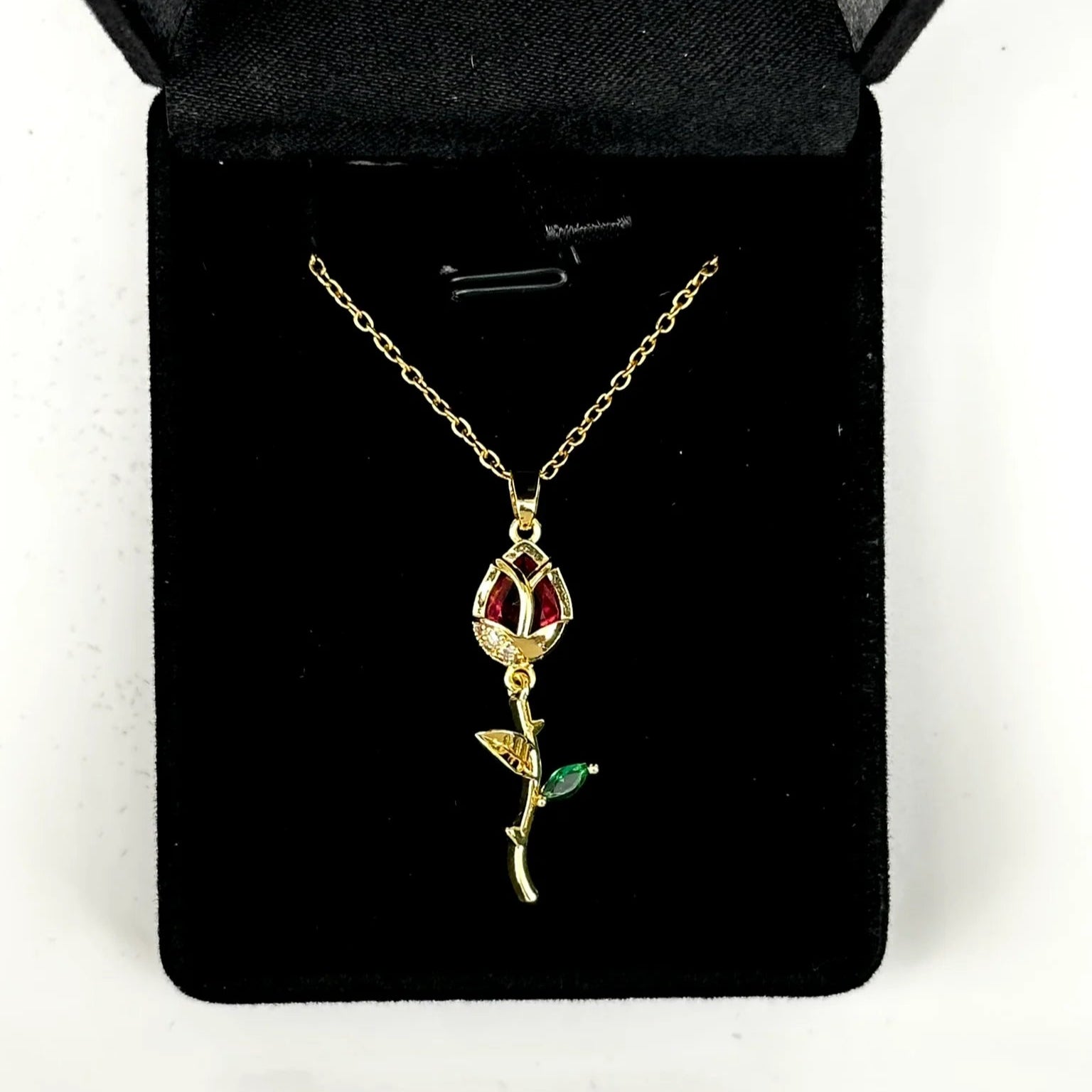 Gold necklace with a rose pendant on a black velvet cushion