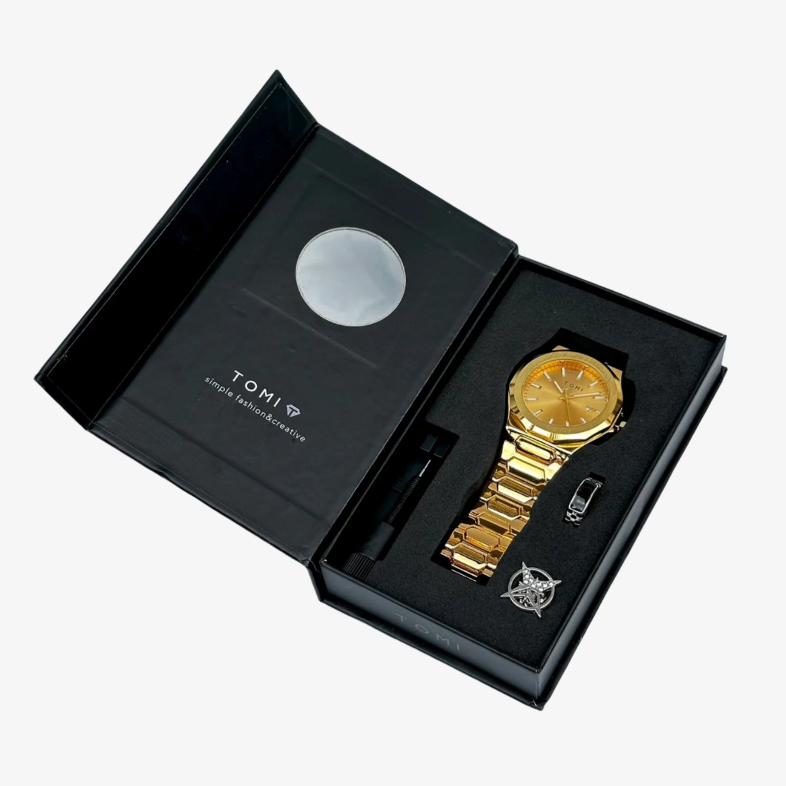 Gold watch and tie clip set in a black box with tomi branding on a light gray background