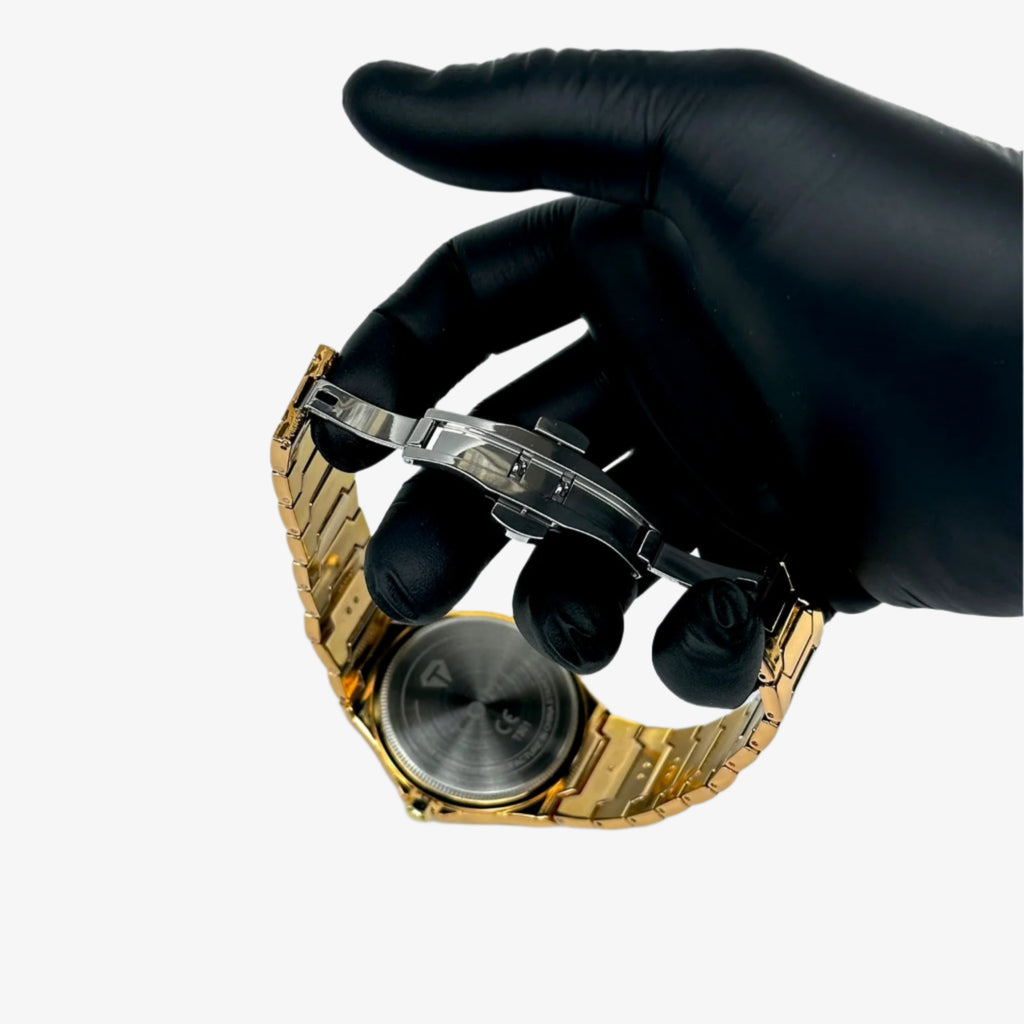 Gold watch being examined with a magnifying glass by a gloved hand on a white background