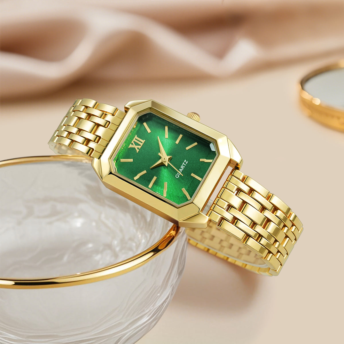 Gold wristwatch with green face on a beige fabric background