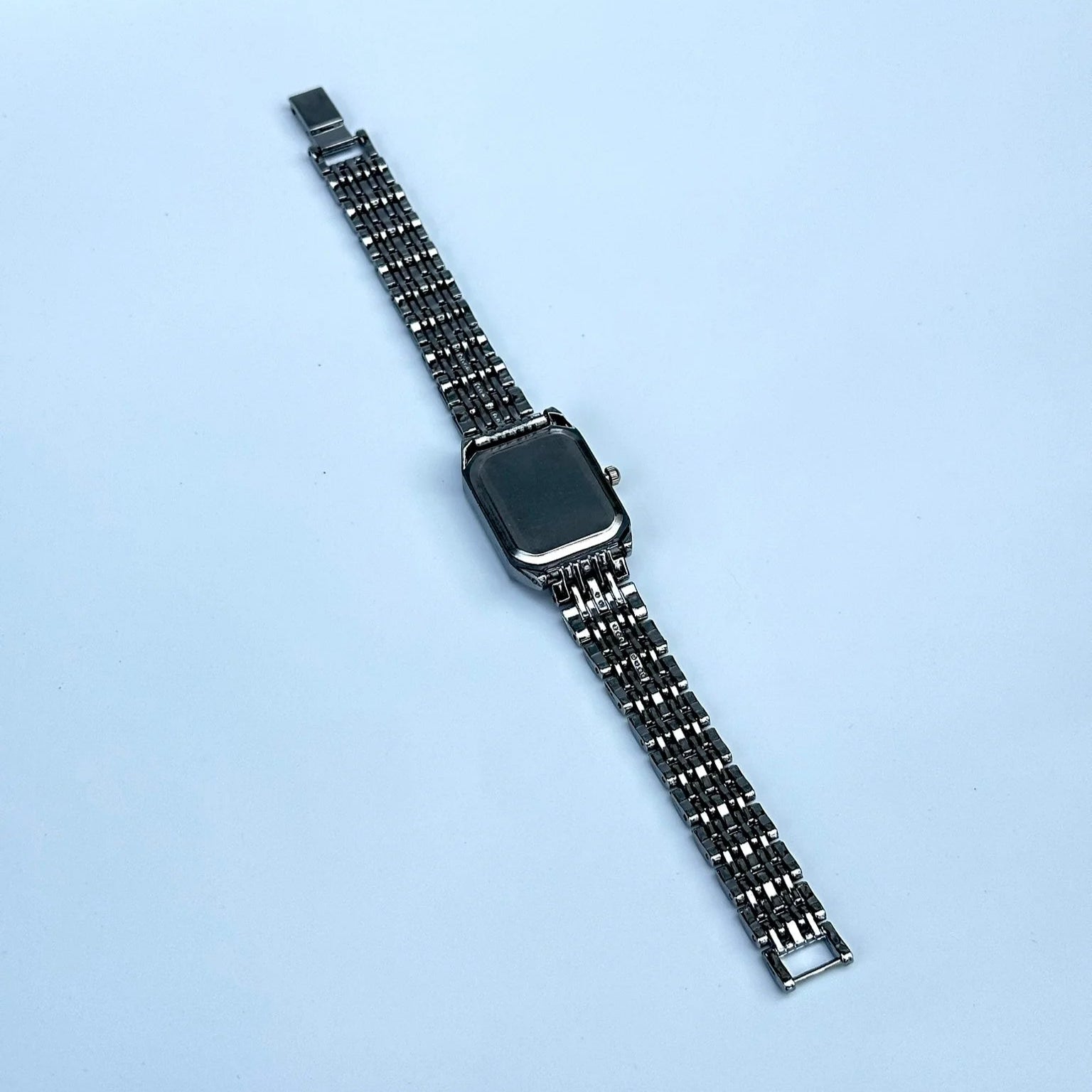Metallic watch strap on a light blue background