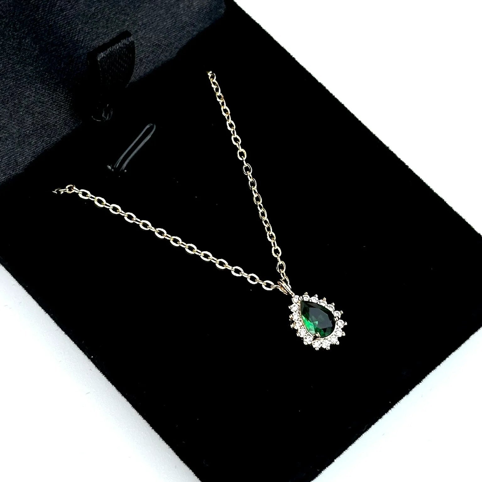 Necklace with a green gemstone pendant on a black jewelry box