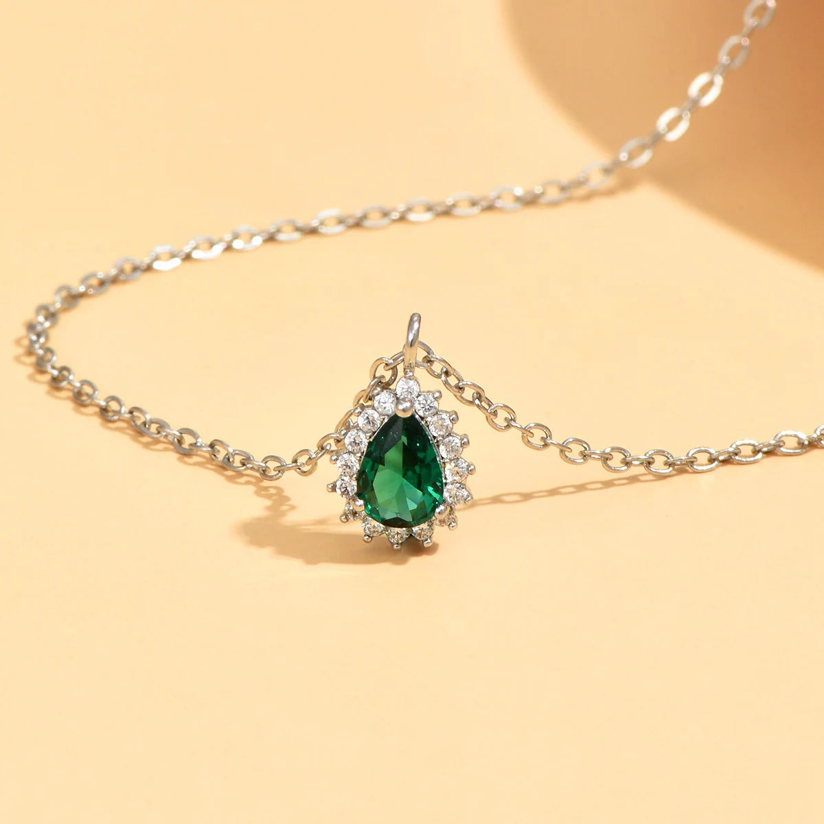 Necklace with a green teardrop pendant on a yellow background