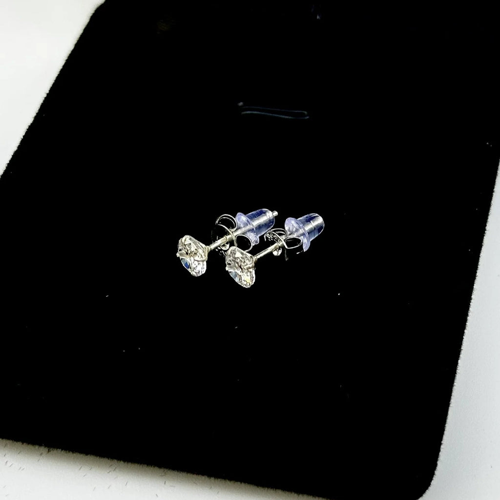 Pair of silver stud earrings on a black jewelry box