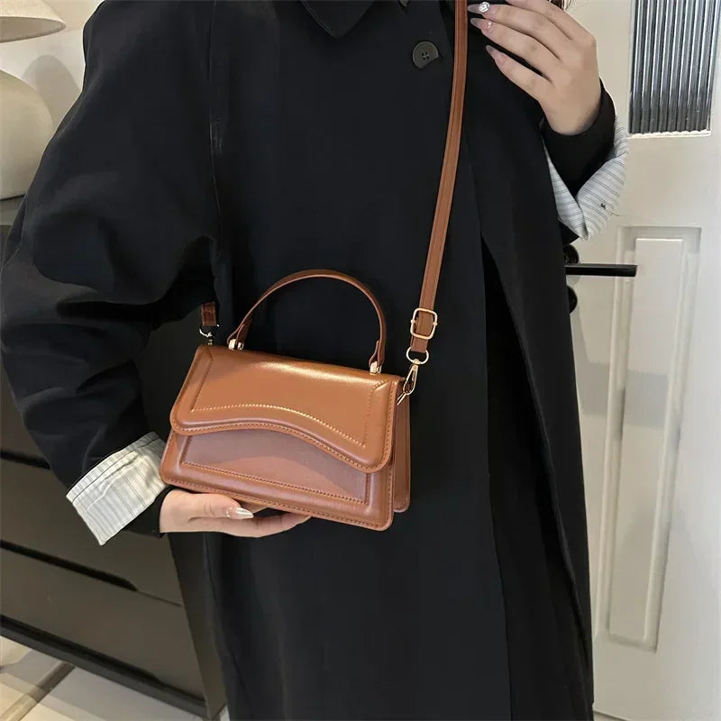 Person holding a brown handbag with a plain background