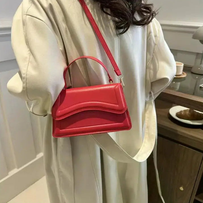 Red handbag held by a person in a casual setting