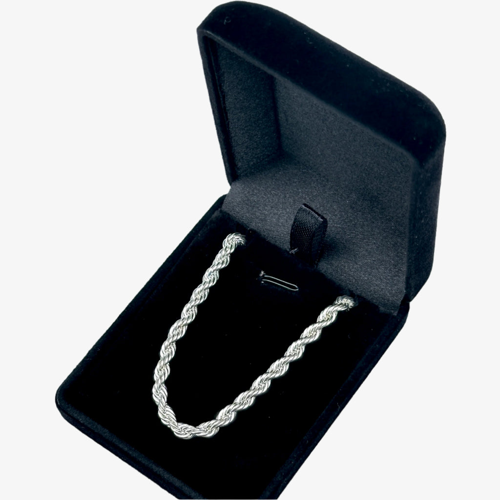 Silver necklace in an open black jewelry box on a light gray background