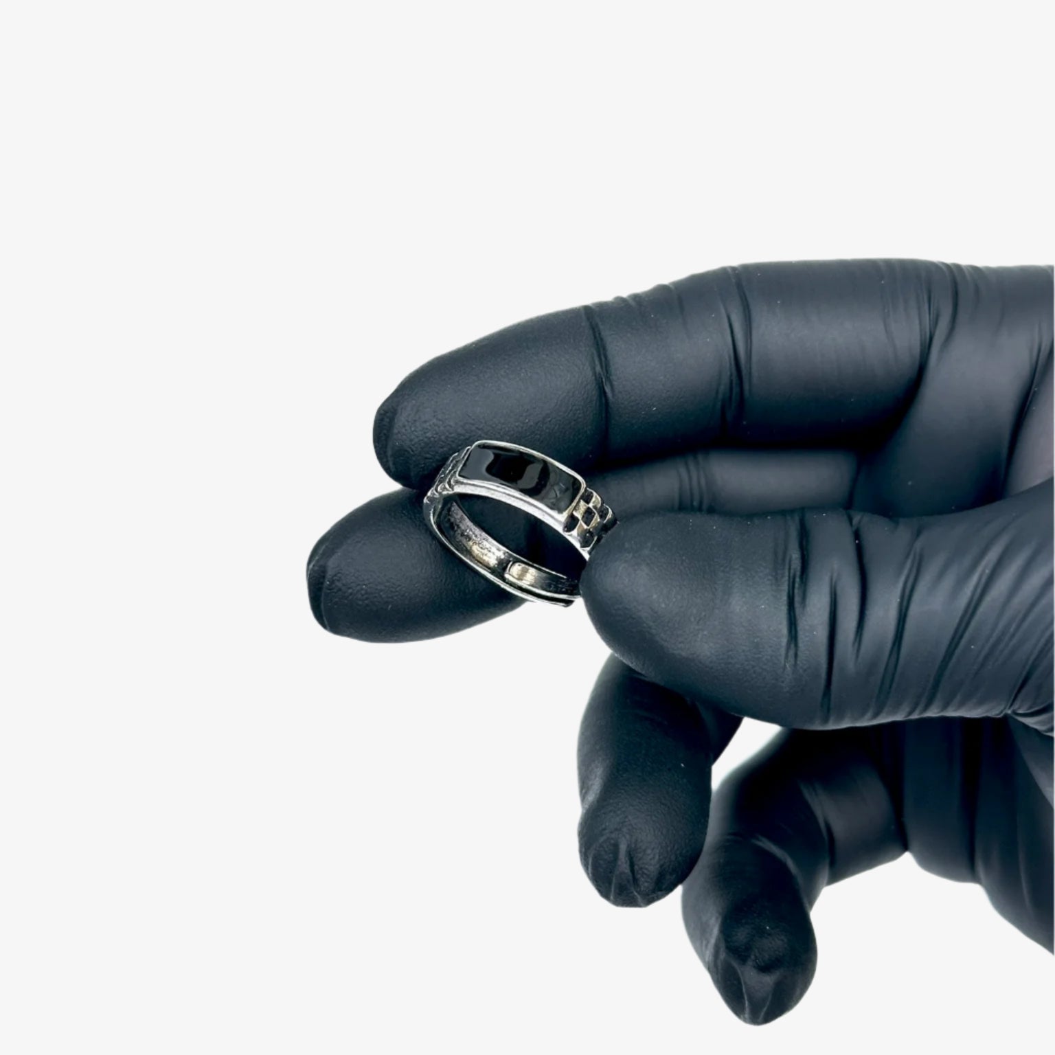Silver ring held by a gloved hand against a light blue background