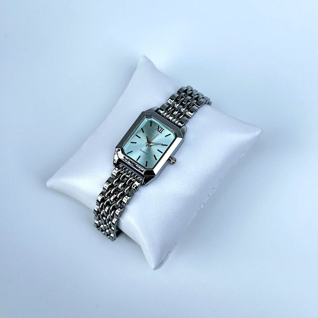 Silver watch on a white cushion against a light blue background