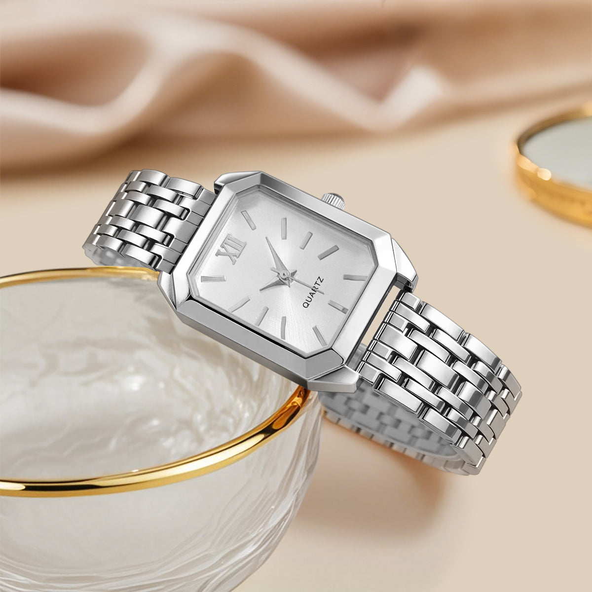 Silver watch with a metal band on a beige fabric background