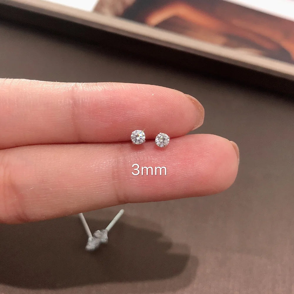 Small silver earrings on a person's finger with '3mm' text