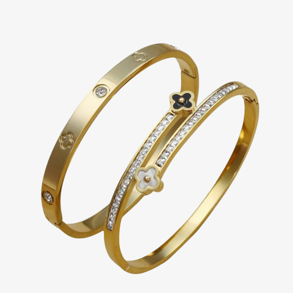 Two gold bangles with floral designs and small stones on a white background