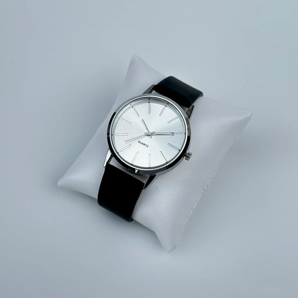 Watch with a black strap on a white cushion against a light gray background